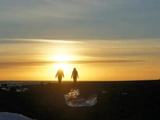 Two people silhouetted against a golden sunset.
